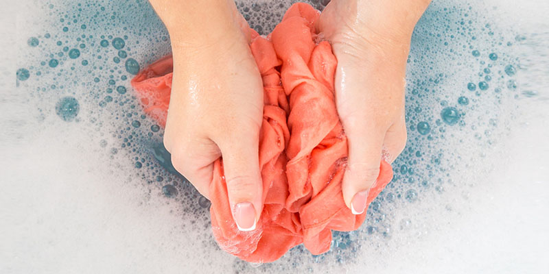 شستن لباس با دست در آب و کف